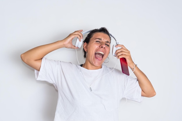 Une femme avec un t-shirt blanc crie avec une bouteille d'alcool rouge.