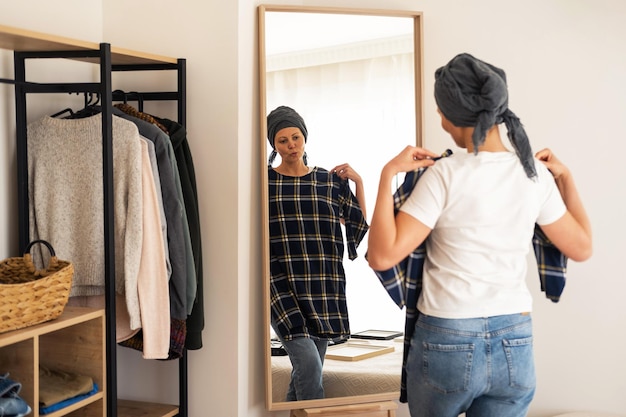 Une femme en T-shirt blanc essaie des vêtements devant un miroir