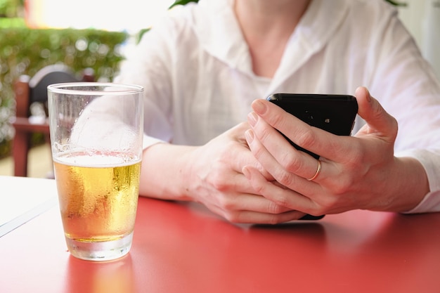 Femme à une table de café de rue tient un smartphone dans ses mains