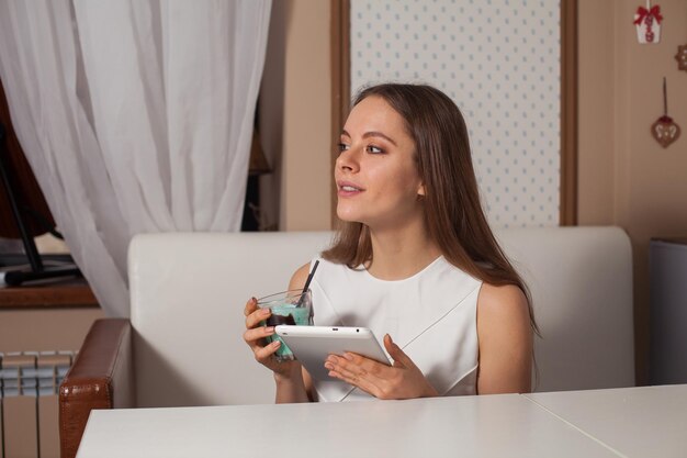 Femme avec tablette et boisson au café