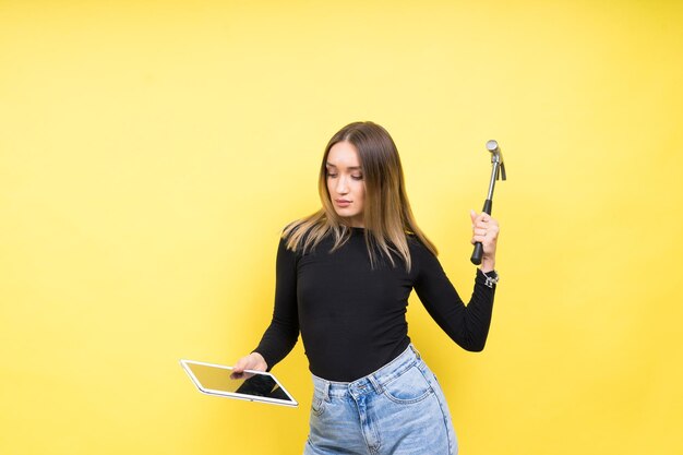 Femme avec tablette et marteau Studio éclairage fond jaune espace de copie isolé