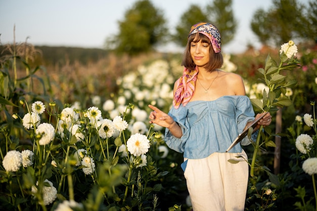 Femme avec une tablette numérique sur une ferme florale à l'extérieur