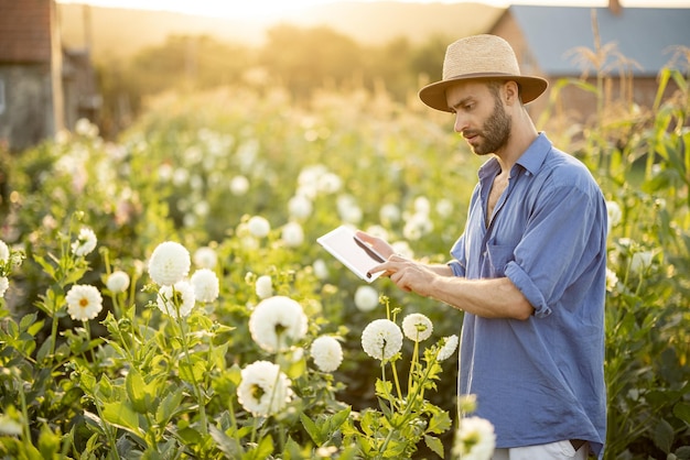 Femme avec une tablette numérique sur une ferme florale à l'extérieur