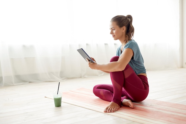 Une femme avec une tablette et un verre au studio de yoga.