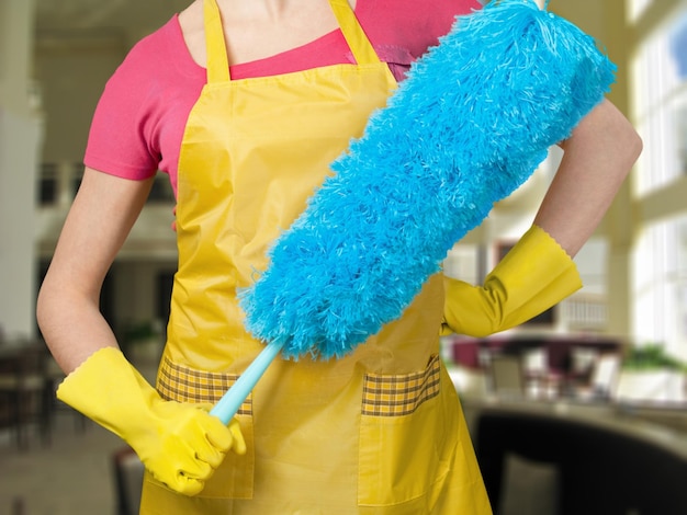 Femme en tablier avec des gants en caoutchouc et un aspirateur