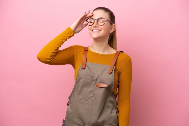 Femme avec tablier isolé sur fond rose souriant beaucoup