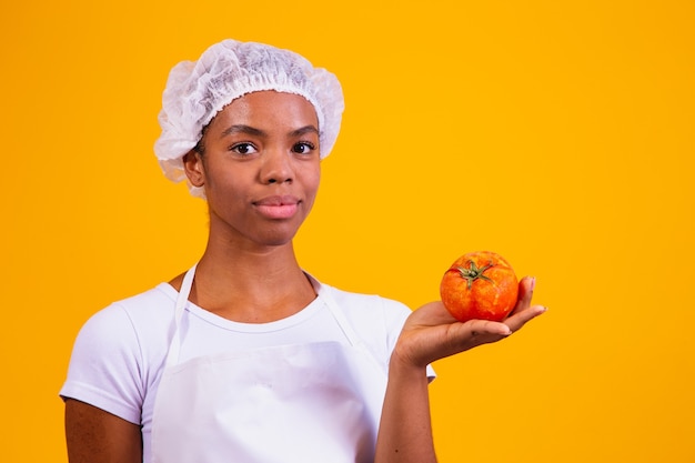 Femme en tablier tenant une tomate. Recettes de tomates