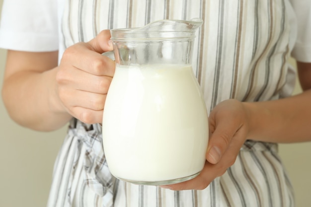 Femme en tablier tient un pichet de lait, gros plan