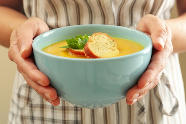 Femme en tablier tient la soupe de potiron, gros plan