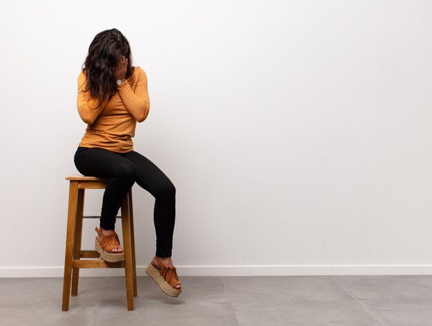 Femme sur un tabouret couvrant son visage