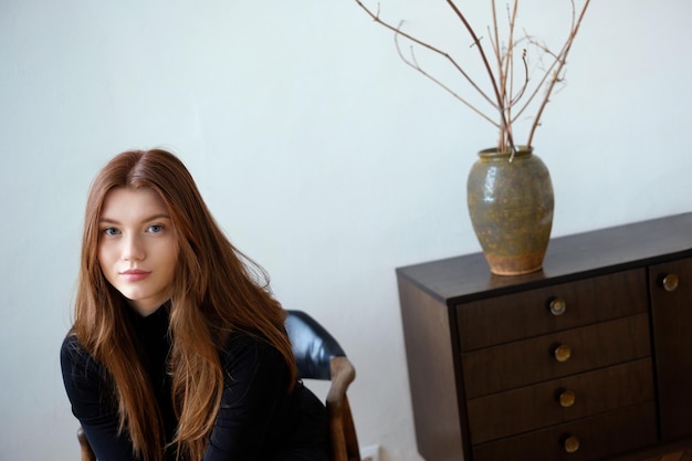 femme de taille plus avec un beau maquillage de jour et des cheveux bien entretenus à la maison assise dans une robe brune