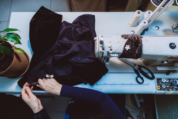 Une femme tailleur coud des vêtements une veste à la mode en tissu de velours sur une machine à coudre dans son atelier