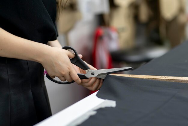 Photo femme tailleur coupant du tissu avec des ciseaux au bureau