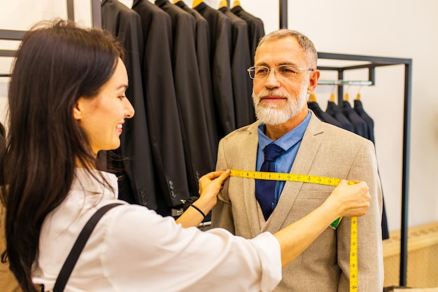 Une femme tailleur professionnelle essayant un costume sur mesure pour un homme âgé