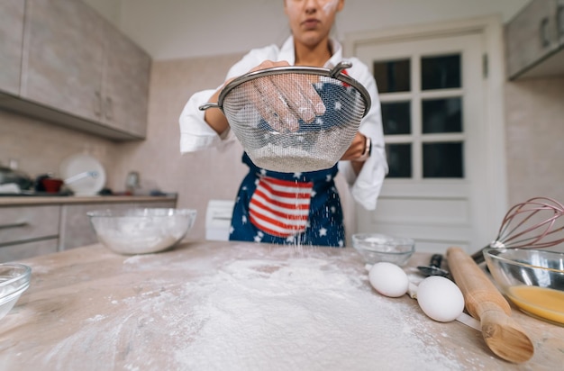 Femme tamisant la farine à travers le tamis Mise au point sélective