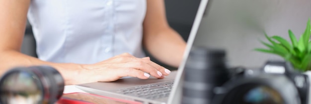 Femme tapant sur un clavier d'ordinateur portable à table avec des objectifs de caméra concept de création de contenu en gros plan