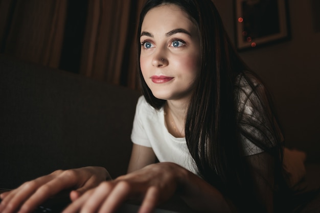 Femme tape sur un clavier d'ordinateur portable et regarde sur l'écran