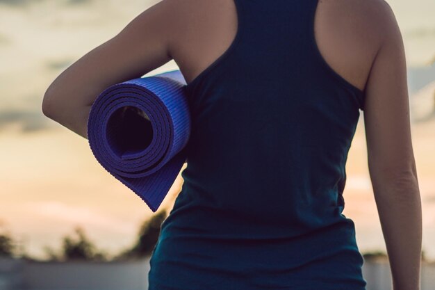 Femme avec tapis prêt à contre le coucher du soleil.