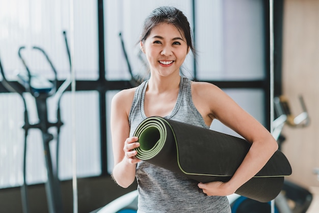 femme avec tapis de yoga à la salle de fitness