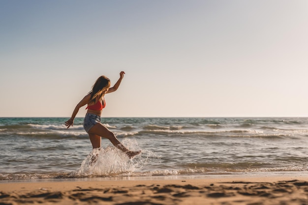 La femme tapote joyeusement son pied sur l'eau de mer