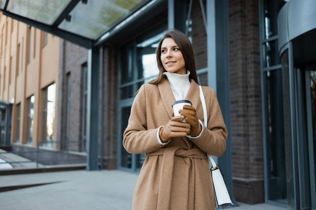 Femme avec une tasse de café sur le fond du bâtiment du centre d'affaires