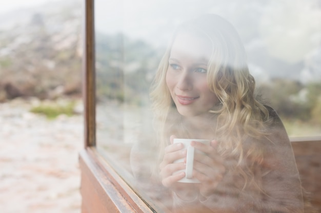 Femme avec une tasse de café regardant par la fenêtre de la cabine