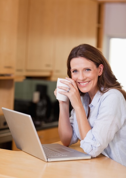 Femme avec une tasse à côté de l&#39;ordinateur portable