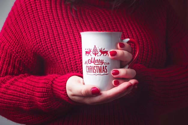 Femme avec une tasse de Joyeux Noël et un pull rouge