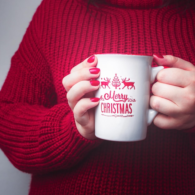 Femme avec une tasse de Joyeux Noël et un pull rouge