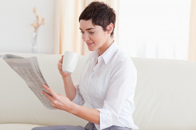 Femme avec une tasse en lisant les nouvelles