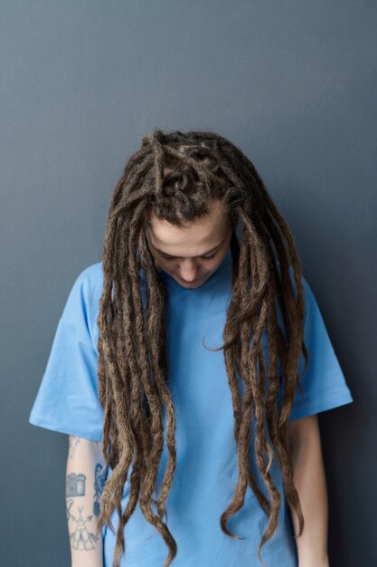 Photo une femme tatouée avec de longs dreadlocks debout avec la tête grise vers le bas