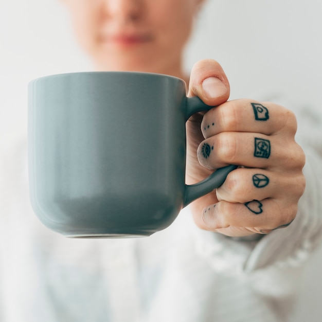 Femme tatouée souriante prenant une tasse de café