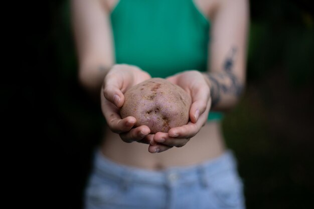 femme tatouée tenant une pomme de terre à deux mains