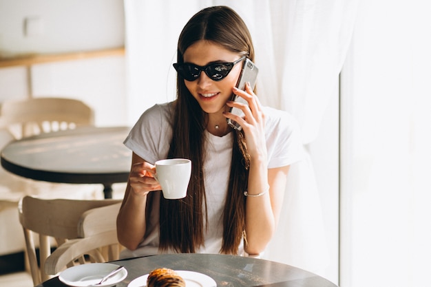 Femme avec téléphone café et croissant