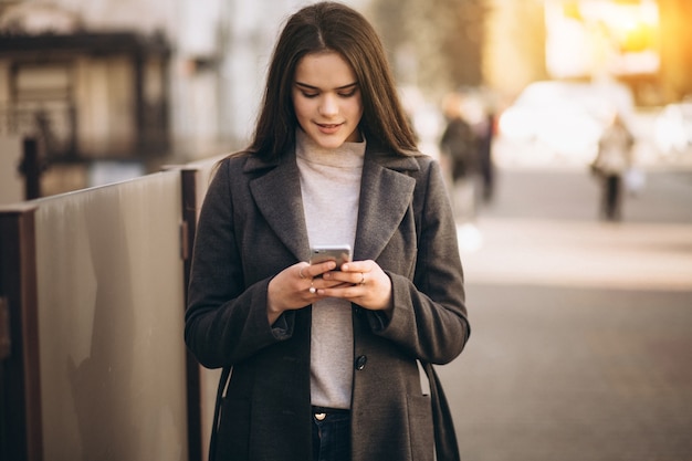 Femme avec téléphone dans le manteau dans la rue