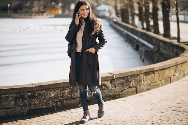 Femme avec téléphone dans le parc au bord du lac en hiver