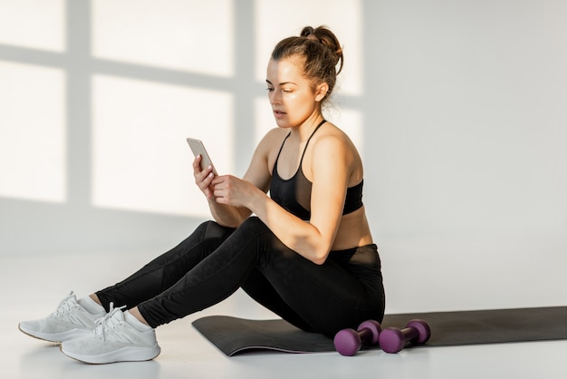 Femme avec téléphone sur un entraînement de fitness