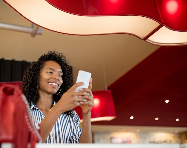 Femme sur le téléphone mobile en attente de son vol à l'aéroport