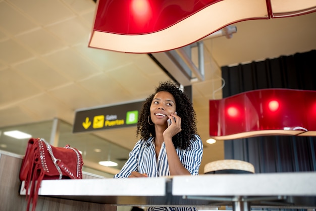 Femme sur le téléphone mobile en attente de son vol à l'aéroport