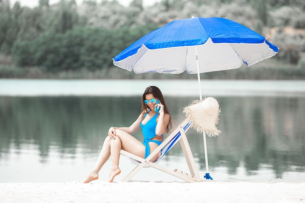 Femme avec téléphone portable sur la plage à l'été