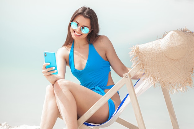 Femme avec téléphone portable sur la plage à l'été