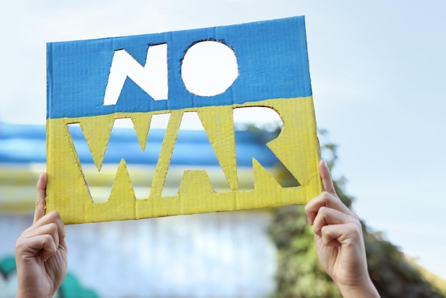 Photo femme tenant une affiche aux couleurs du drapeau ukrainien avec des mots pas de guerre à l'extérieur libre