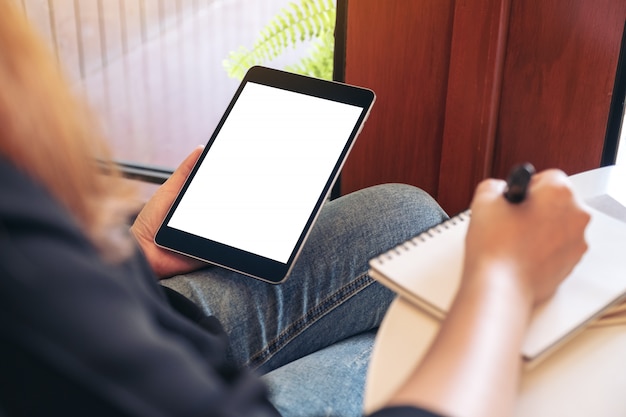 Femme tenant et à l'aide de tablet pc noir avec écran de bureau blanc vierge