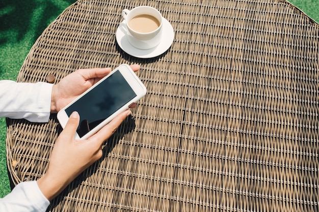 Femme tenant et à l'aide de téléphone intelligent avec écran vide vide noir à la cafétéria