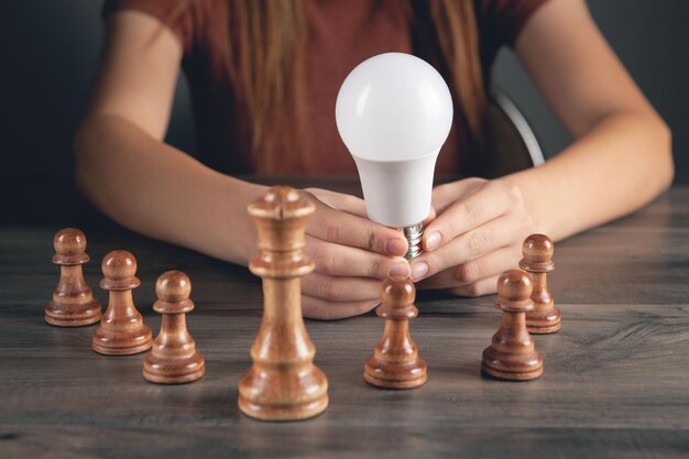 Femme tenant une ampoule près des pièces d'échecs