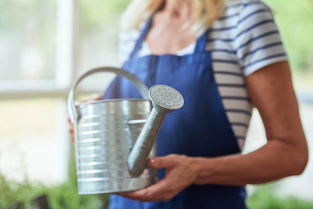 Femme tenant un arrosoir dans les mains debout en serre