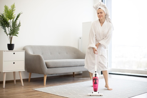 Femme tenant un aspirateur et montrant le pouce vers le haut à l'intérieur