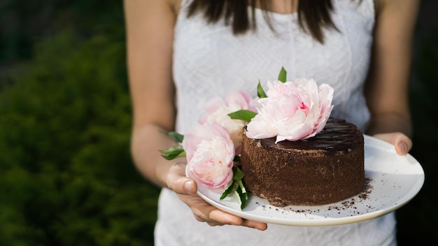Femme tenant une assiette avec un gâteau au chocolat Swets décoré de fleurs