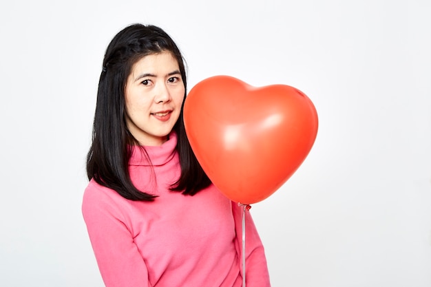 Femme tenant un ballon en forme de coeur rouge