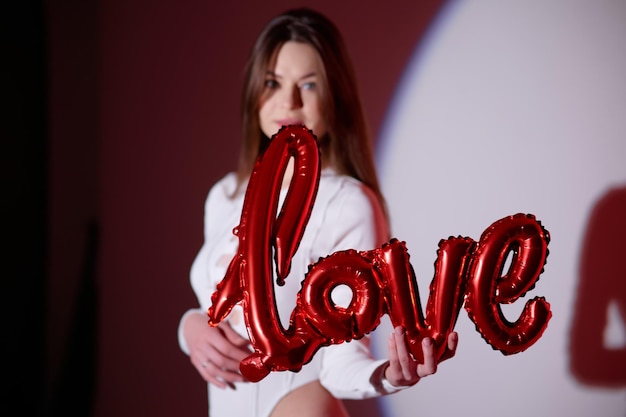 Femme tenant un ballon rouge avec le mot amour dessus